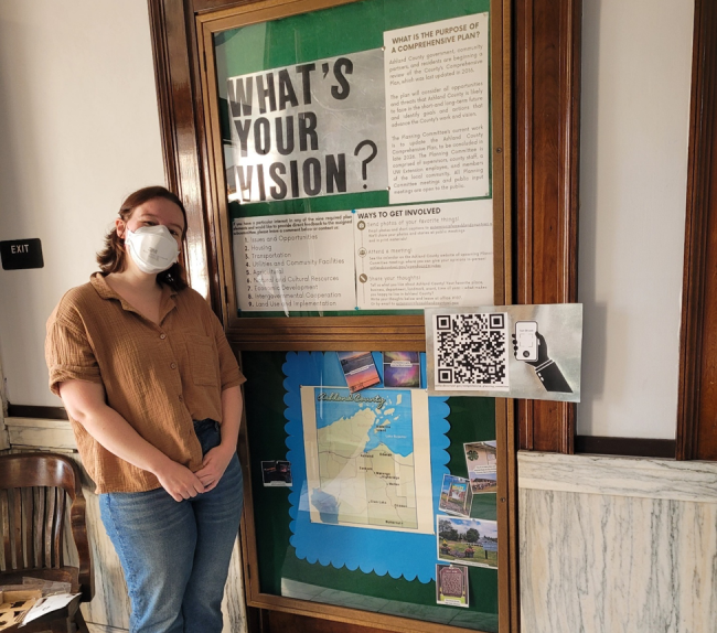 a woman poses in front of a display titled "what's your vision?" 